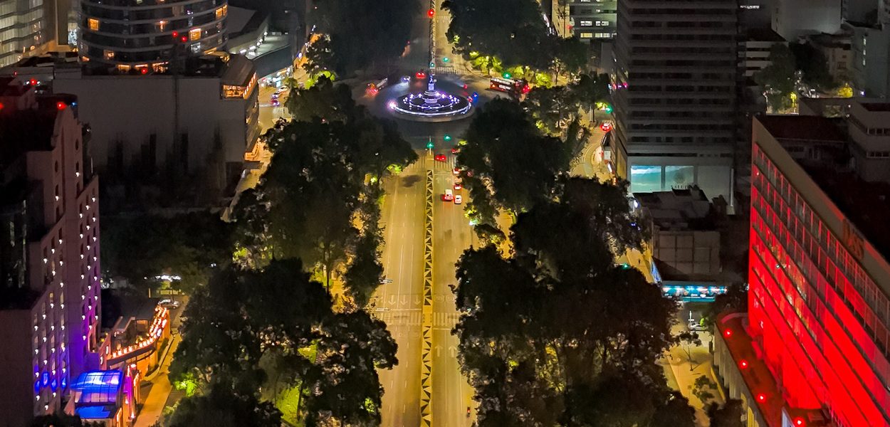Paseo de la Reforma at night from above, the avenue and its lit buildings running toward the city